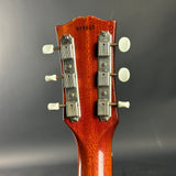 Close-up of a guitar headstock with tuning pegs on a gray background