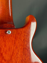Close-up of a wooden guitar body with a visible screw on a dark background