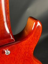 Close-up of a red electric guitar's body with a blurred dark background