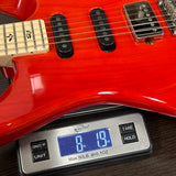 Red electric guitar on a digital scale displaying weight