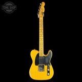 A classic Fender Telecaster electric guitar in a natural yellow wood finish, shown from the front against a solid black background. The guitar features a black pickguard, chrome hardware, and a headstock with six tuning pegs.