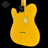 A close-up of a yellow Fender Telecaster electric guitar body, showing the natural wood grain, a worn white pickguard, and a black Fender logo plate, set against a solid black background.