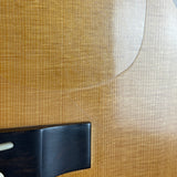 Close-up of a guitar body showing the natural wood grain finish and part of the dark bridge.