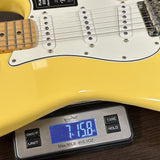 Yellow electric guitar on a digital scale displaying weight