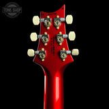 Close-up rear view of a red electric guitar headstock with six gold and silver tuning pegs and white tuning keys, shown against a black background. A Tone Shop watermark is visible in the top left corner.