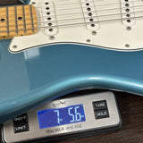 Blue electric guitar on a digital scale displaying weight.