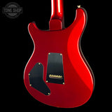 The rear view of a glossy red electric guitar against a solid black background, featuring black pickguards and gold hardware.