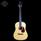 A natural wood acoustic guitar with a dark red pickguard, shown vertically against a solid black background. A 'TONE SHOP' watermark is visible in the top-left corner.