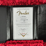 A Fender authenticity certificate insert displayed inside a black leather case lined with plush red velvet. The certificate is addressed to the Fender Custom Shop and features the Fender logo in gold script at the top.