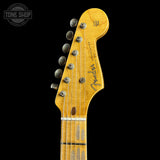 Close-up of the headstock of a Fender electric guitar, showing the maple wood neck and tuning pegs against a solid black background.