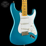 A turquoise blue electric guitar with a white pickguard and maple neck, shown against a solid black background. A Tone Shop watermark is visible in the top-left corner.