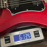 Red electric guitar on a digital scale displaying weight