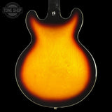 Back of a sunburst electric guitar with 'Tone Shop' logo in the corner.