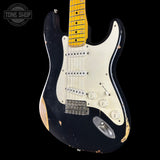 Black electric guitar with a worn finish on a black background, featuring the Tone Shop logo.