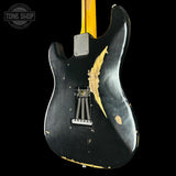 Black electric guitar with gold accents on a black background, featuring 'Tone Shop' logo.