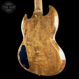 The back of an electric guitar with a glossy natural wood finish, featuring a black pickguard and gold hardware, shown against a solid black background.