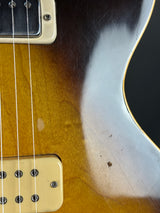 Close-up of a guitar's neck and headstock with a worn finish.