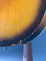 Close-up of a guitar's soundboard with visible wood grain and a blue background
