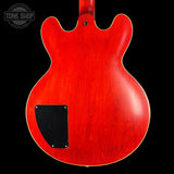 Red electric guitar body with a black pickguard on a black background, featuring 'Tone Shop' logo.