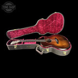 Acoustic guitar in a red-lined case with 'Tone Shop' logo.