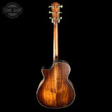 Back view of a brown acoustic guitar on a black background with 'Tone Shop' logo.