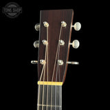 Close-up of a guitar headstock with tuning pegs on a black background, featuring the Tone Shop logo.