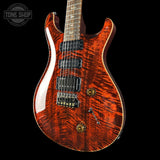 Electric guitar with a red and brown wood finish on a black background, featuring the Tone Shop logo.