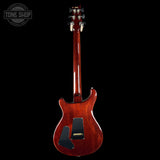 Back view of a red electric guitar on a black background with 'Tone Shop' logo.