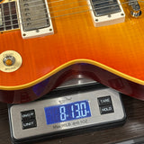 Orange electric guitar on a digital scale displaying weight
