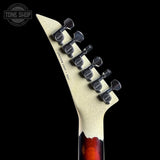 Close-up of a guitar's headstock with tuning pegs on a black background, featuring the Tone Shop logo.