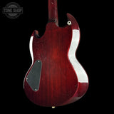 The rear view of an electric guitar with a glossy dark red cherry finish, featuring a white body contour, a black pickguard, and a gold-toned output jack, set against a solid black background.