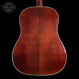 Back view of a wooden acoustic guitar with 'Tone Shop' logo.