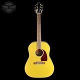 A yellow acoustic guitar with a dark brown neck and headstock, shown against a solid black background. A Tone Shop watermark is visible in the top-left corner.