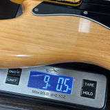Close-up of a guitar body resting on a digital scale displaying 9.05 lbs.