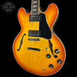 Electric guitar with a sunburst finish on a black background, featuring the Tone Shop logo.
