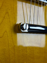 Close-up of a guitar's headstock with tuning pegs on a wooden surface