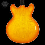 Back view of a sunburst electric guitar with 'Tone Shop' logo.