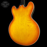 Back view of a sunburst electric guitar with 'Tone Shop' logo.