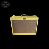 A vintage-style yellow guitar amplifier speaker cabinet with a brown mesh grille and a silver carrying handle, shown against a solid black background. A 'TONE SHOP' watermark is visible in the top-left corner.