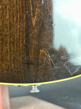 Close-up of a dark brown wood-grain guitar body with visible scratches on the glossy finish and a silver tuning peg on the right edge.