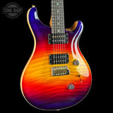 A double-cutaway electric guitar with a vibrant flame-in-the-wood finish transitioning from purple and blue at the upper left, through red and orange, to yellow on the lower right. The guitar is shown against a solid black background with a Tone Shop watermark in the top-left corner.