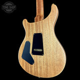 The back of an electric guitar with a natural wood finish and black pickguard, shown against a solid black background with a Tone Shop watermark in the top left corner.