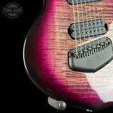 Close-up of an electric guitar body showing a vibrant magenta and brown flamed maple finish, black pickups, and a black bridge, set against a solid black background with a Tone Shop watermark in the top left.