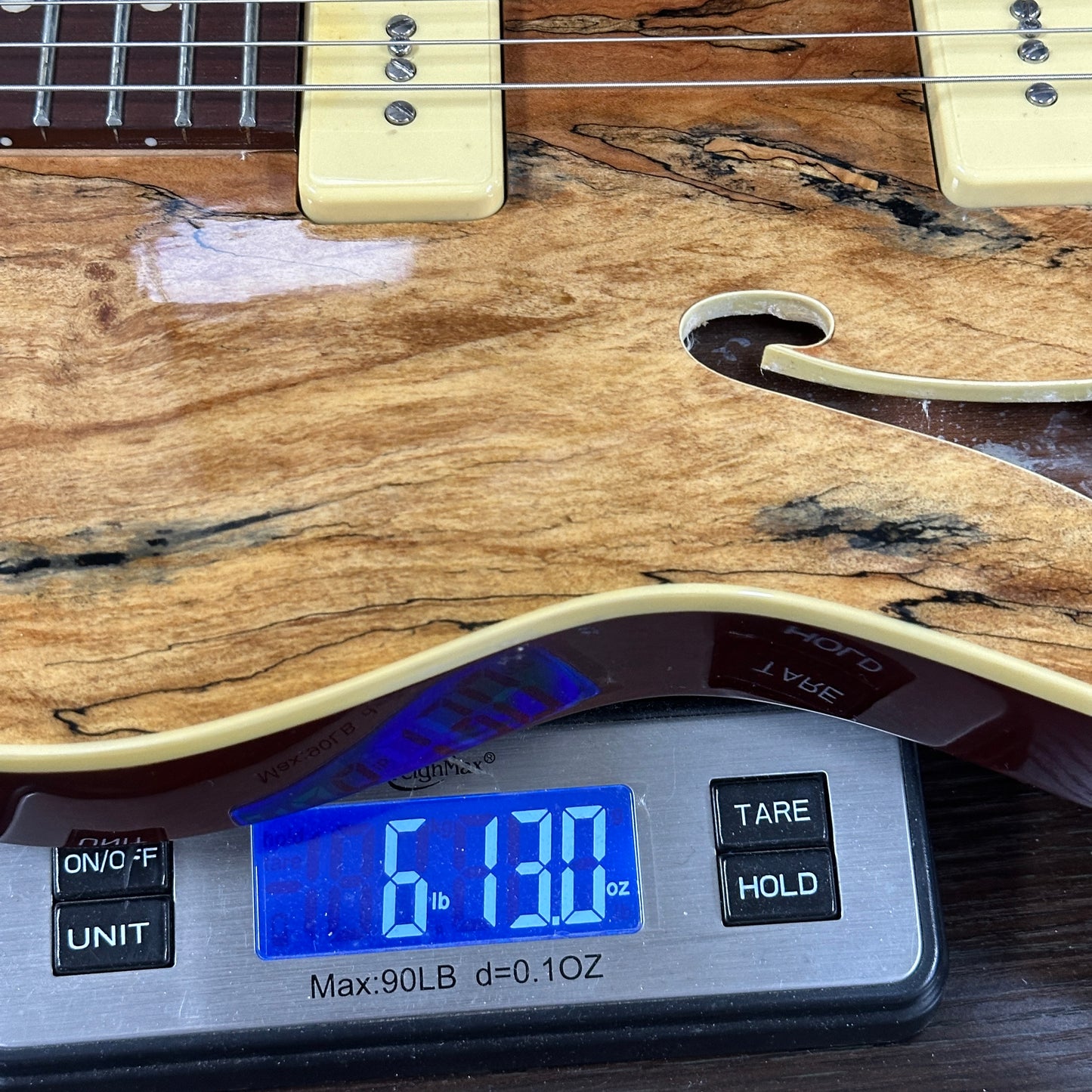 Used Michael Kelly 59 Thinline Spalted Maple on scale displaying weight.
