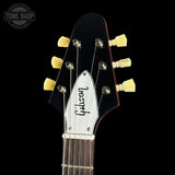 Close-up of a Gibson electric guitar headstock against a black background, showing six cream-colored tuning pegs, a white Gibson logo plate, and part of the dark fretboard.