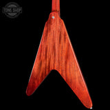 Close-up of the back of an electric guitar showing a glossy reddish-brown wood body with a distinctive angular tail shape, photographed against a solid black background. A Tone Shop watermark is visible in the top-left corner.