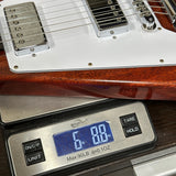 A close-up of a guitar body and pickups resting on a digital scale to show weight, with the scale reading 6.88 lbs.