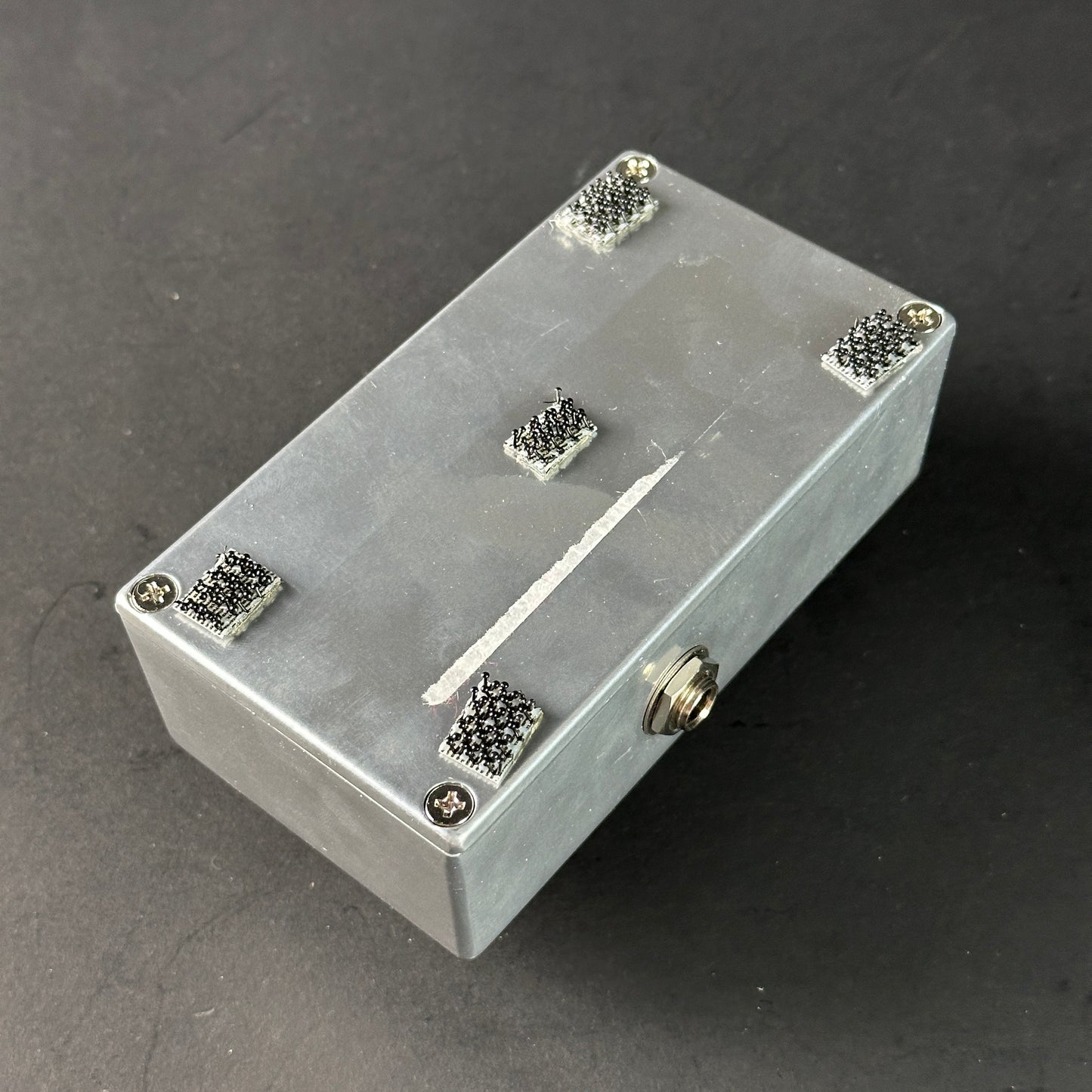 Metallic rectangular box with star-shaped cutouts on a dark surface