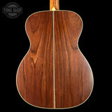 Back view of a wooden acoustic guitar with 'Tone Shop' logo.