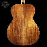 Back view of a wooden acoustic guitar with 'Tone Shop' logo.